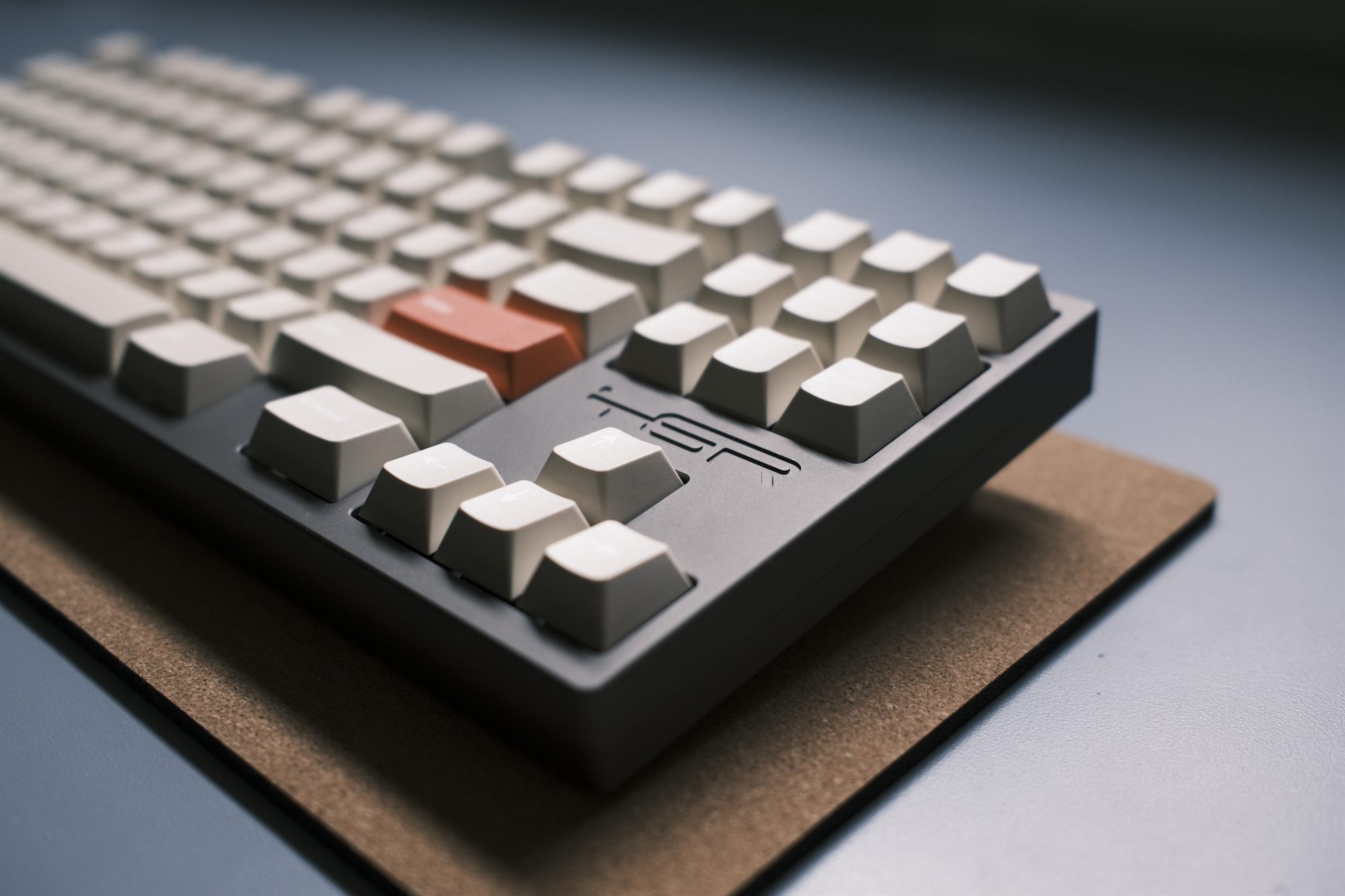 TGR Shi keyboard, three-quarter view, gray case with bone keycaps and a burnt-orange Enter key