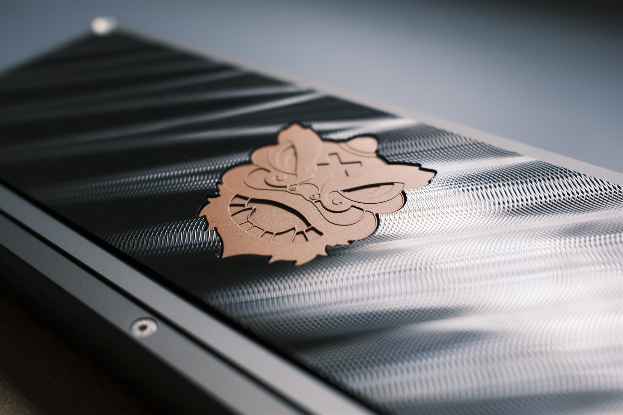 Macro of a copper guardian-lion badge inlaid in machined stainless steel